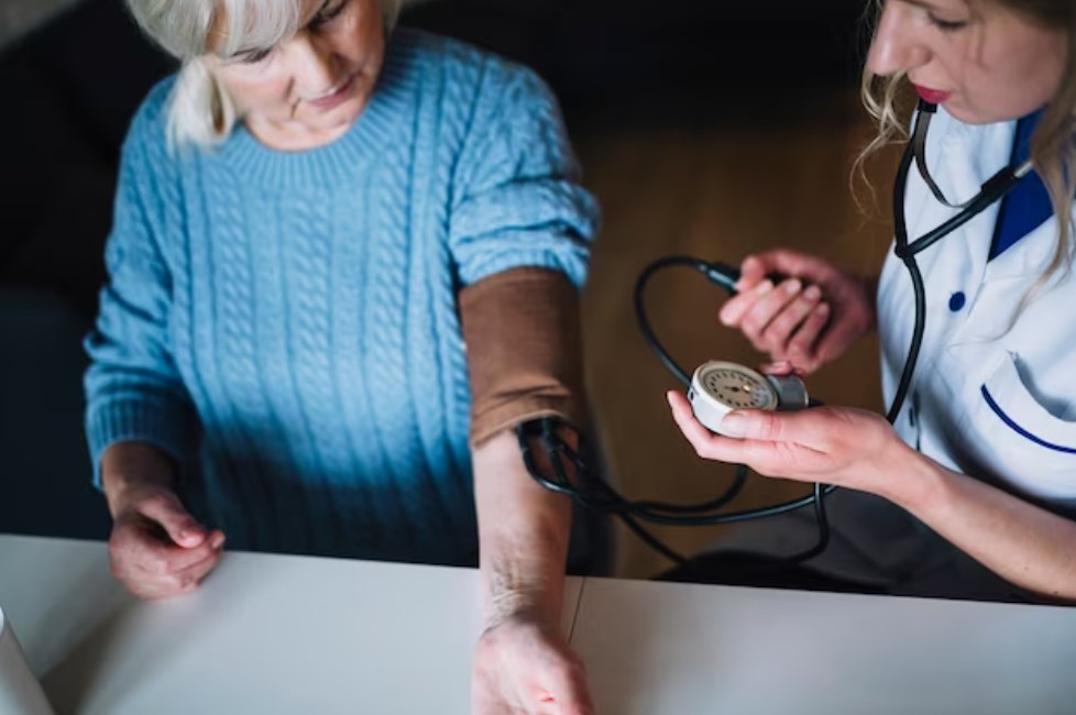 a female doctor checking the blood pressure of her old patient in a nursing home